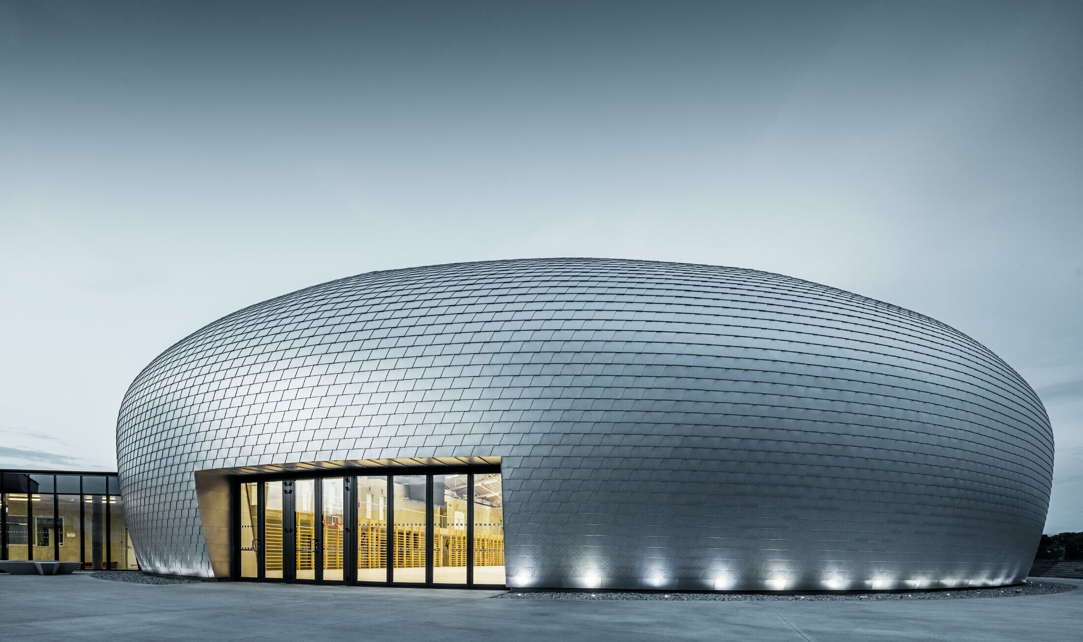 Foto van de sporthal in Tsjechië in de vorm van een UFO bekleed met de PREFA gevelschindel in naturel blank.