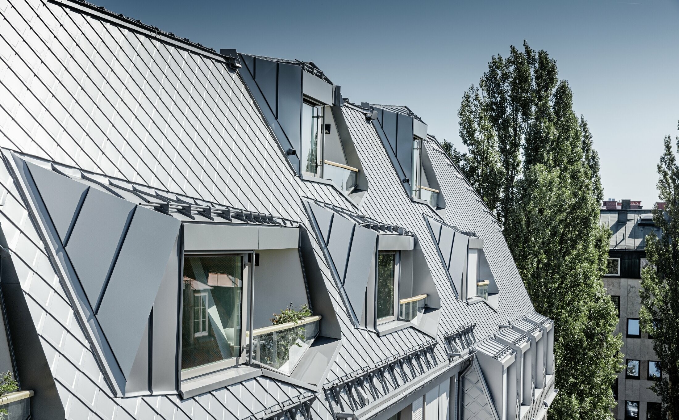 Gerenoveerde dakappartementen met royale loggia's van een woon- en winkelcomplex op de hoek van de Leopoldstraße en Hohenzollernstraße in München. Dakbedekking met PREFA-daklosanges