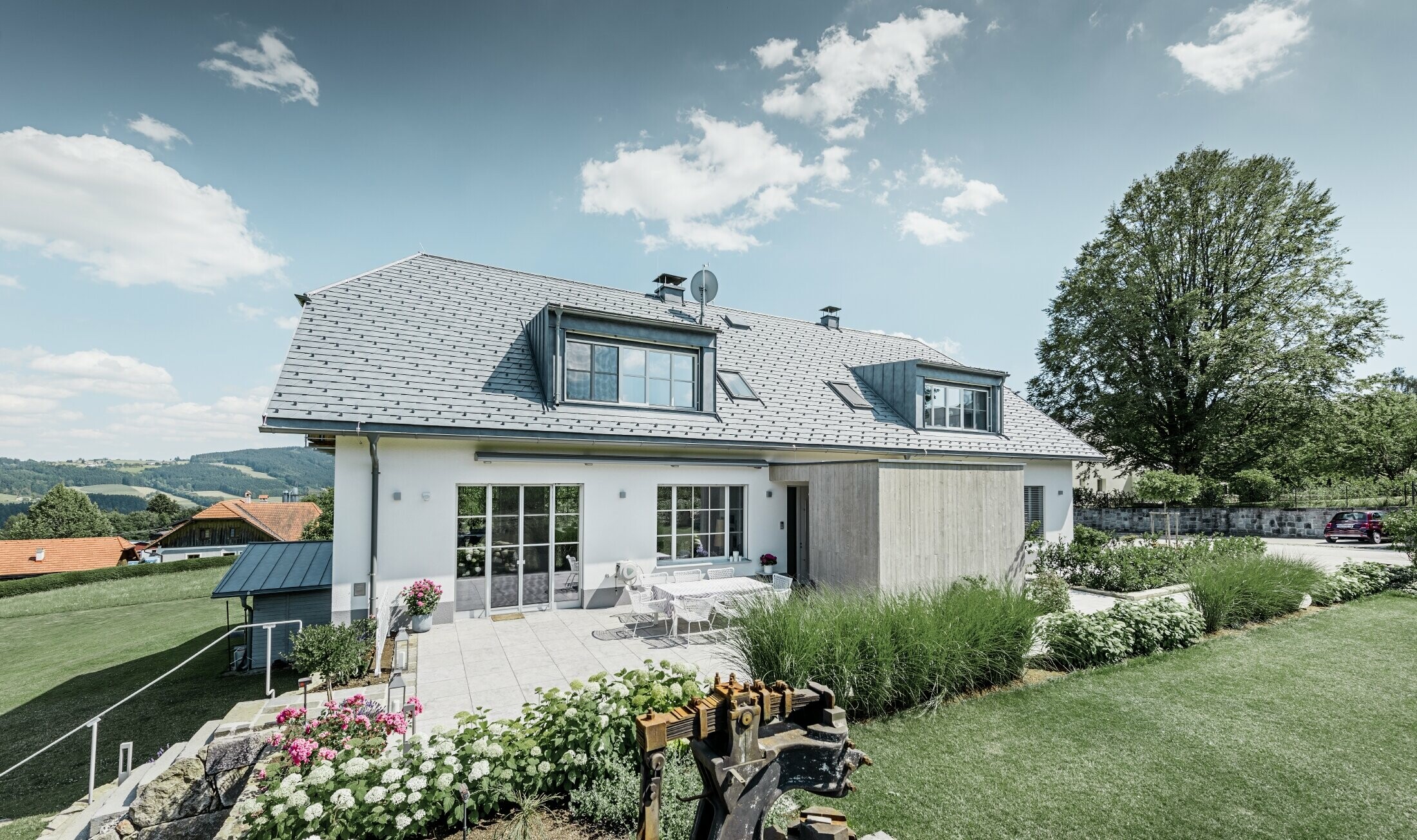 Klassieke eengezinswoning met schilddak met wolfseinden, dakrenovatie met PREFA dakschindels in steengrijs met mooi aangelegde tuin en ruim terras.