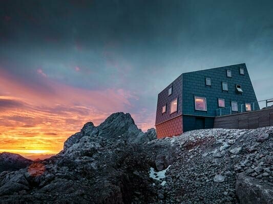 Außergewöhnliche Architektur in den Bergen: die Seethalerhütte am Dachstein eingedeckt mit dem PREFA Dach- sowie Fassadenpaneel Fx.12 in Steingrau.