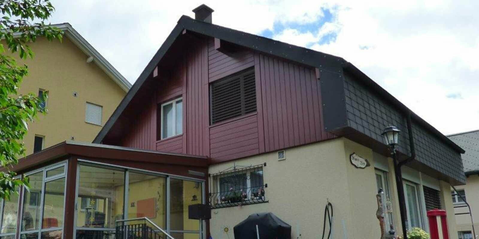 Rénovation de façade du pignon à l’aide de Sidings PREFA imitation bois, pose à la verticale, avec jardin d’hiver et façade jaune