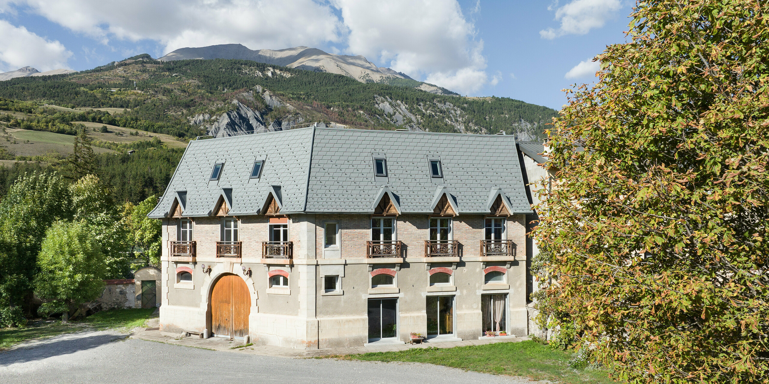 La vaste toiture d'une propriété à Barcelonnette, en France, a été rénovée avec le bardeau de toiture PREFA en P.10 gris souris.