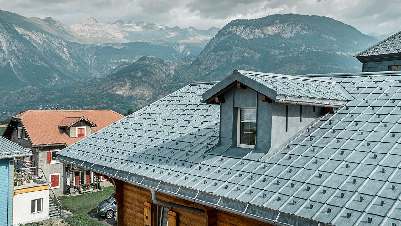 Zadeldak met dakkapel; op het dakvlak is het metalen dak van PREFA gelegd - de dakpan is in steengrijs. De dakkapel is bekleed met de haakse staande fels van PREFA in steengrijs.