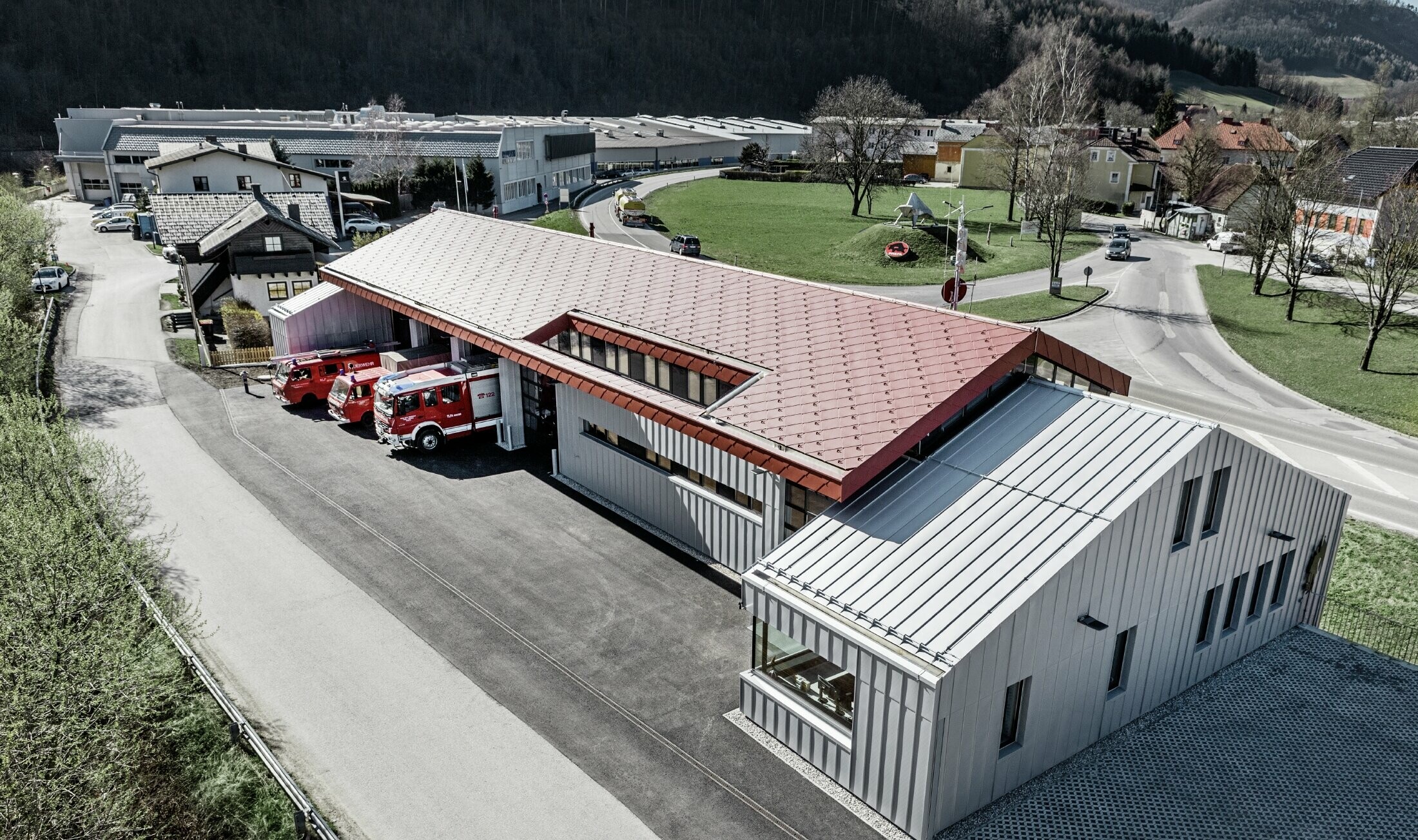 Opname van de bedrijfsbrandweer in Marktl/Lilienfeld in vogelperspectief. Van het linker gebouwgedeelte is het complete dak en de gevel bekleed met de losange 44x44 in oxiderood. Het rechter gedeelte wordt voorzien van een aluminium schil met Prefalz in zilvermetallic.