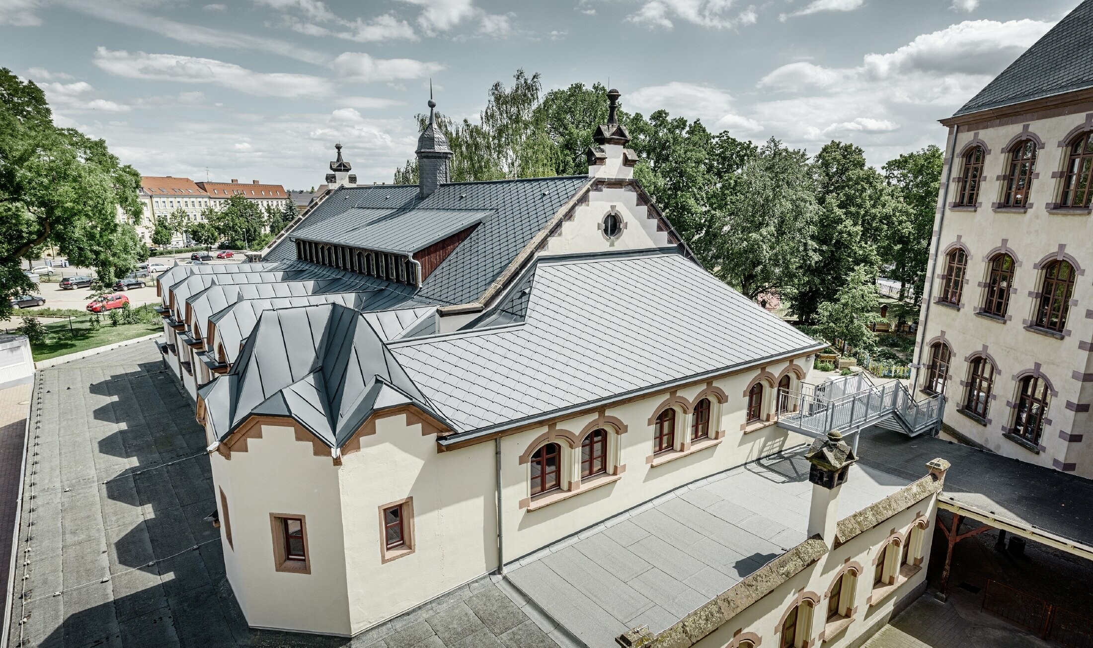 Gerenoveerde turnzaal van Lutherstadt-school in Wittenberg (Duitsland) met PREFA-aluminiumdak bestaande uit daklosanges en staande naad in antraciet