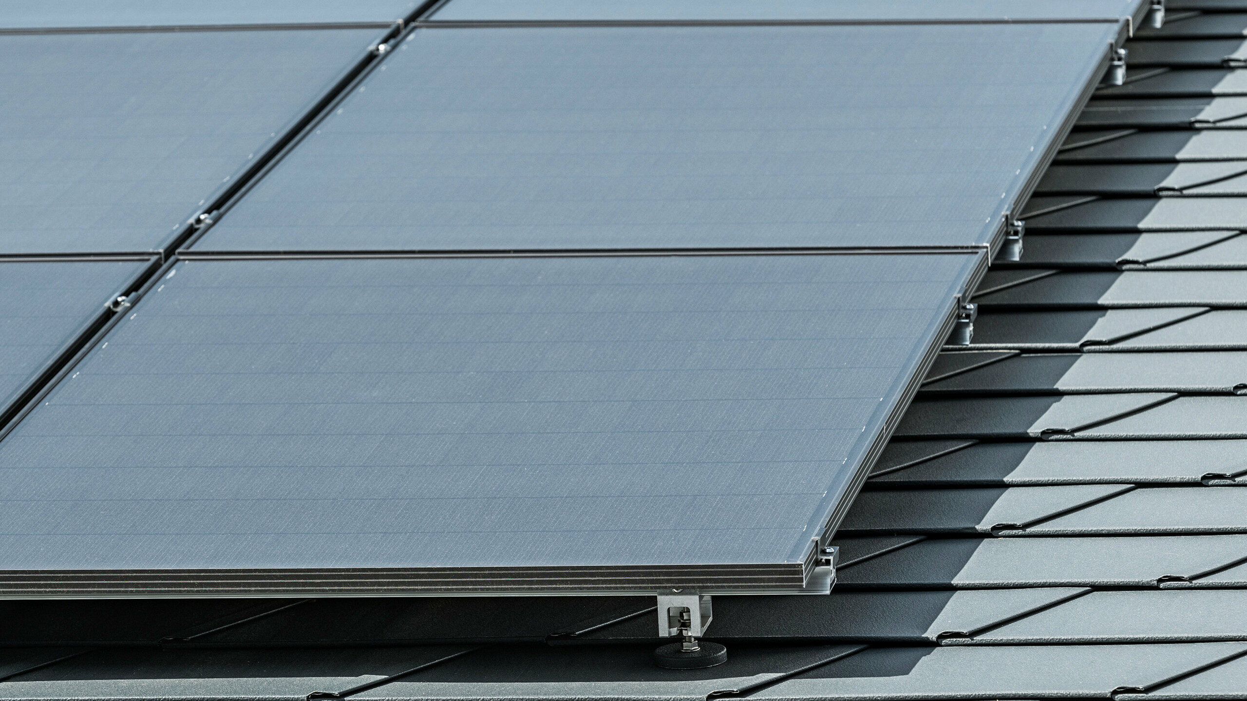 Photovoltaikmodule, befestigt mit den PREFA Solarhaltern Vario, auf den PREFA Dachschindeln DS.19 in P.10 Anthrazit  Photo de détail d'une installation photovoltaïque sur bardeaux PREFA DS.19 en P.10 anthracite, montée avec le support solaire Vario PREFA