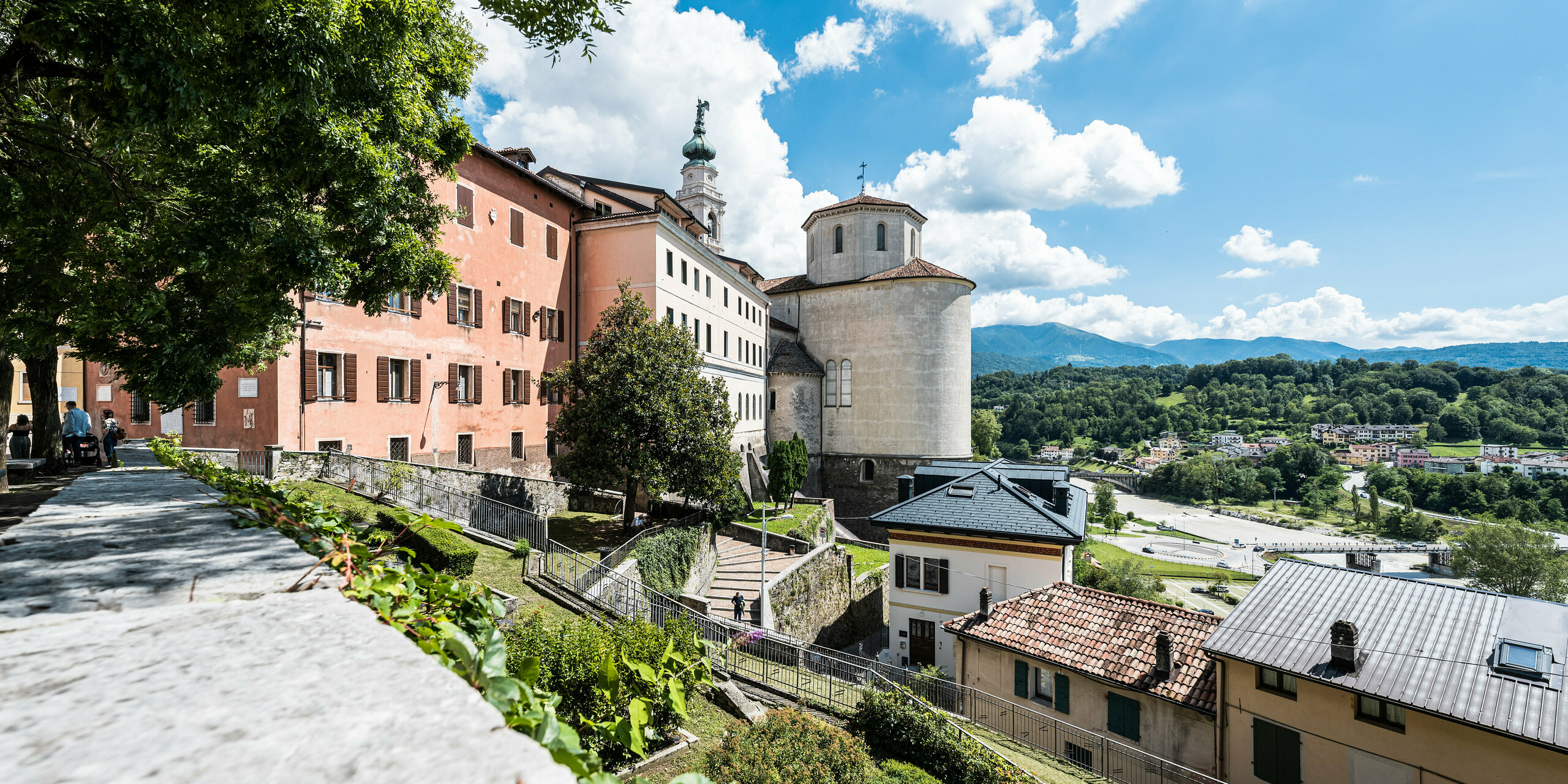 Das historische Stadtbild von Belluno, geprägt durch ein Zusammenspiel von Kultur und Natur, mit Blick auf ein sanft restauriertes Gebäude mit PREFA Aluminiumdachschindeln in Anthrazit, das sich elegant in die pittoreske italienische Berglandschaft einfügt. Die Authentizität des Ortes wird durch die Renovierung unter Beibehaltung der historischen Bausubstanz und der Einführung moderner, langlebiger Materialien wie den PREFA Dachschindeln respektvoll ergänzt.