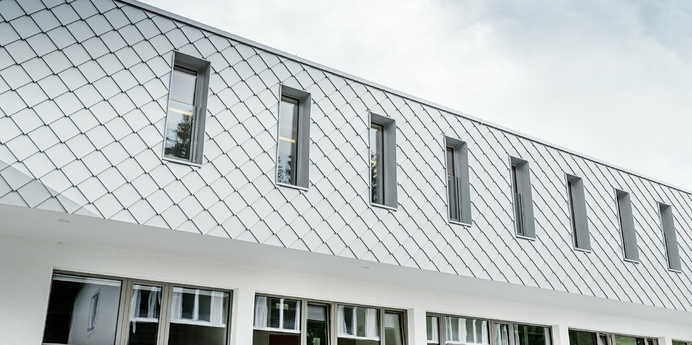 Neu gebauter Kindergarten in Kaprun mit einer modernen Aluminium Fassade mit der PREFA Wandraute in prefaweiss