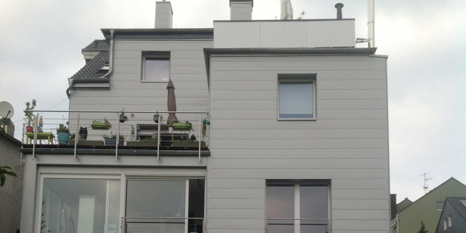 Immeuble d’habitation avec toit plat et terrasse, avec façade récemment rénovée à l’aide de Sidings PREFA