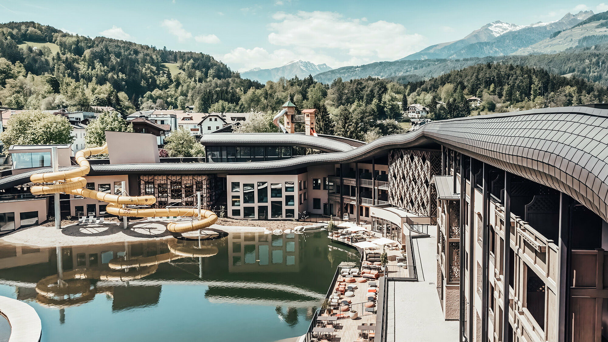 Aperçu de l'hôtel avec le lac et les toboggans. En arrière-plan, on aperçoit le paysage vallonnée. 