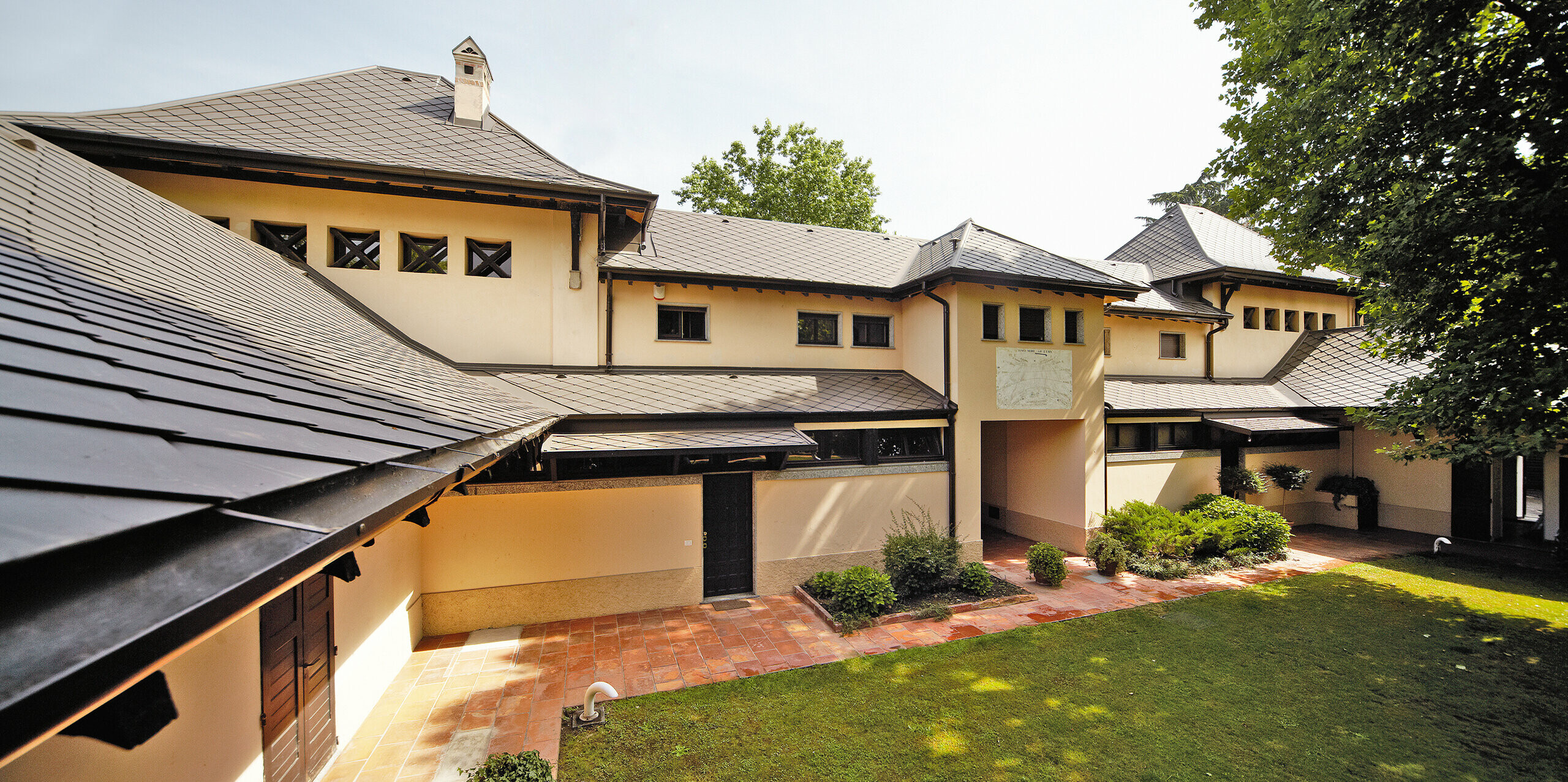 Italienische Villa mit Rautendach in P.10 Braun von PREFA mit beiger Fassadenfarbe mit schattigem Innenhof