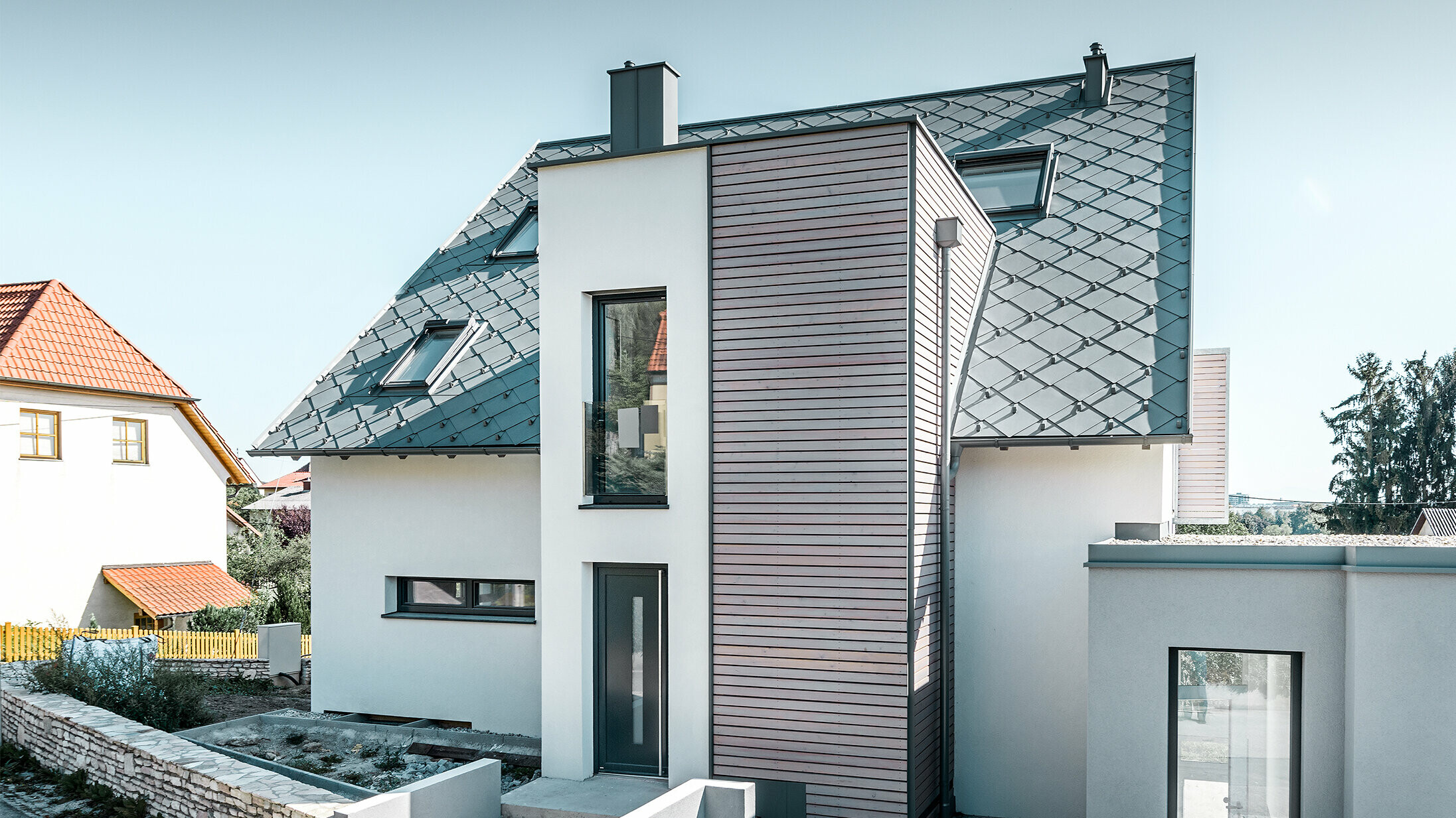 La maison individuelle avec toit à deux pans à Leonding a été entièrement rénovée. La surface de toit a été recouverte de losanges de toiture 44 × 44 PREFA couleur gris souris avec arrêts neige. Le choix s’est porté sur la gouttière suspendue de PREFA, également couleur gris souris. 