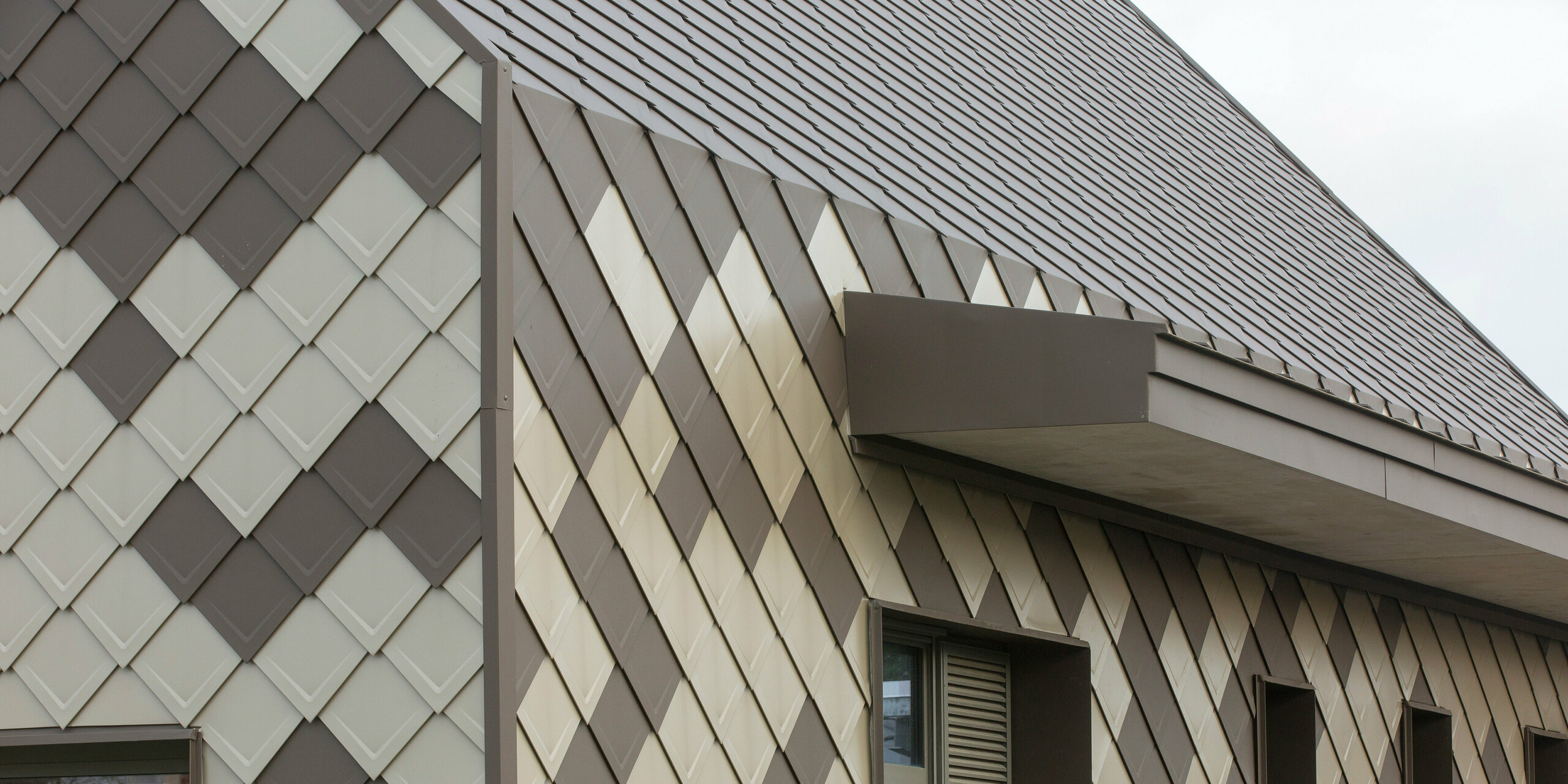 Bords de bâtiment doux au périscolaire à Sessenheim : le bâtiment a été entièrement recouvert de losanges de toiture et de façade PREFA 29 × 29 en brun et bronze.