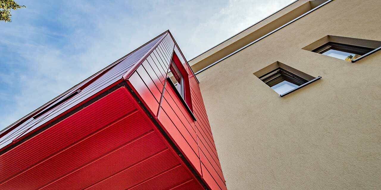 Erker met gelinieerde PREFA sidings in robijnrood aan een moderne eengezinswoning in Wernigerode, hier is het onderaanzicht van de uitstekende aanbouw gefotografeerd.