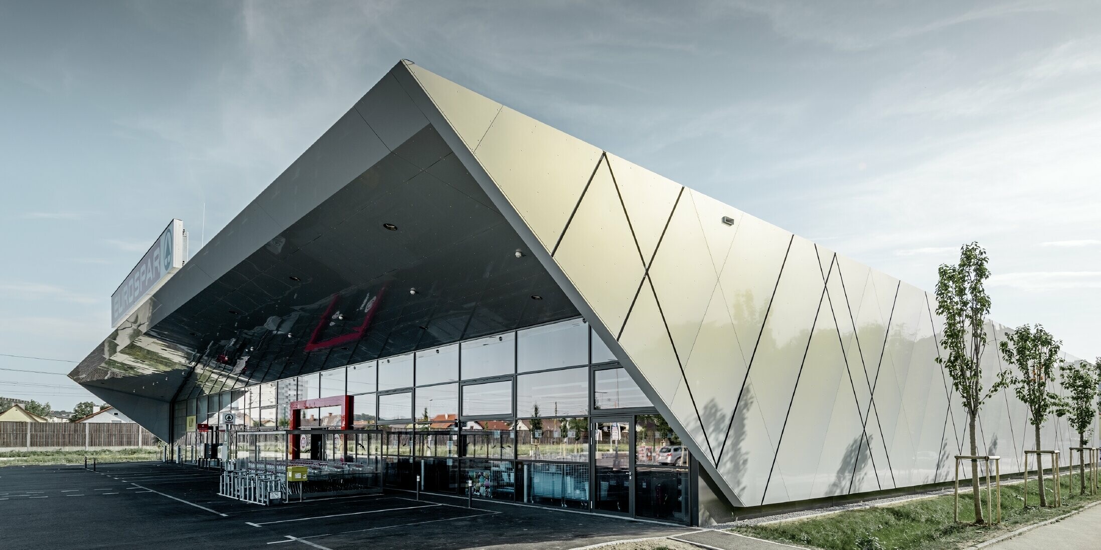 Eingangsbereich der neuen Eurospar Filiale in Wels mit der modernen Fassadenplatte von PREFA in Silver gold; Die Aluminium Verbundplatten schillern in der Sonne je nach Blickwinkel in unterschiedlichen Farben.