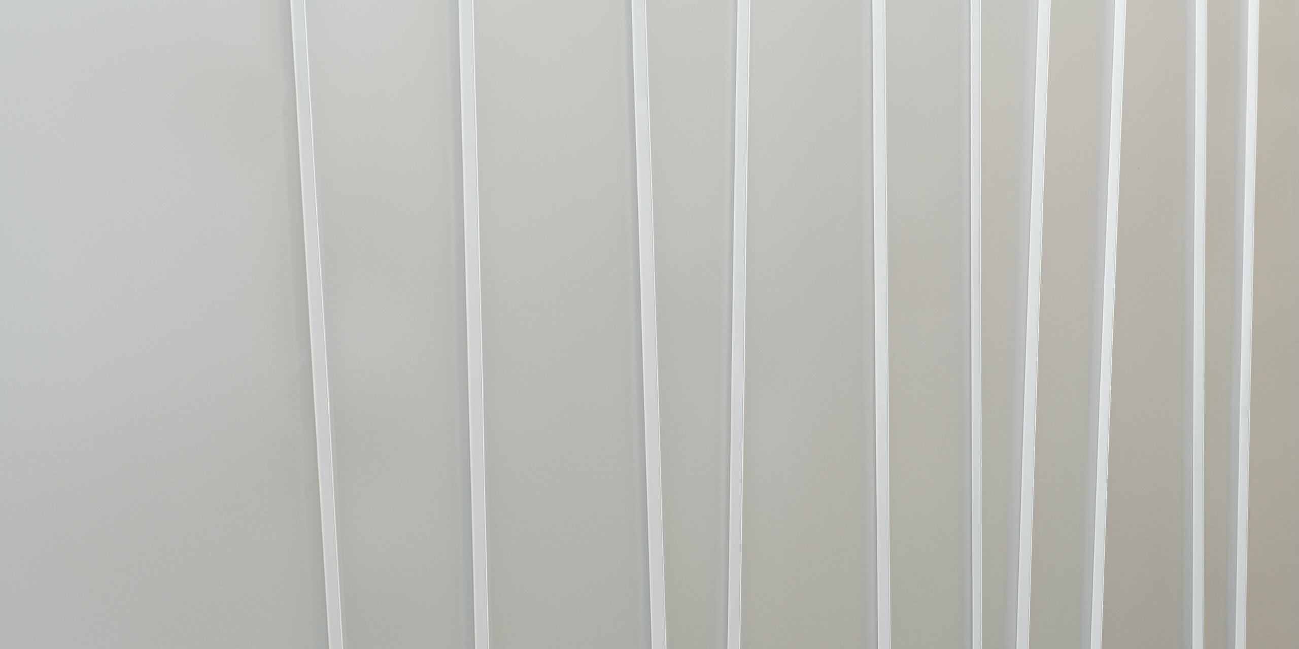 Gros plan d'un système de façade moderne en PREFALZ gris souris avec différentes largeurs de bacs. La texture épurée et minimaliste transmet une sensation d’ordre et un design contemporain.