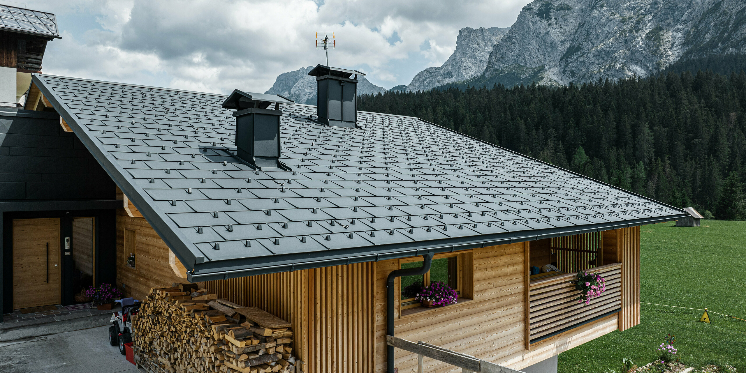 Casa Hoffe in Sappada, Italien, präsentiert ein schwarzes PREFA Dach, Die Dachplatten R.16, fügen sich harmonisch in die ländliche alpine Landschaft ein. Die dunklen, präzise angeordneten Aluminiumplatten kontrastieren stilvoll mit der hellen Holzfassade und sorgen für einen modernen Touch, der die traditionellen Werte des alpinen Wohnens widerspiegelt. Die robusten und langlebigen Materialien versprechen Schutz und eine geringe Wartung in der herausfordernden Bergumgebung.