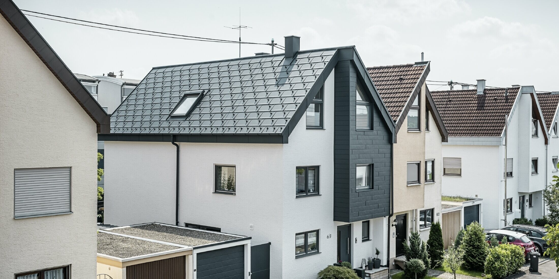 De helft van een twee-onder-een-kapwoning werd al gerenoveerd, met een frisse witte pleistergevel gecombineerd met een PREFA Siding.X gevel in antraciet. Het dak werd bedekt met de PREFA dakpan R.16. Het dakafvoersysteem bestaat uit de vierkante bakgoot inclusief PREFA afvoerbuis.